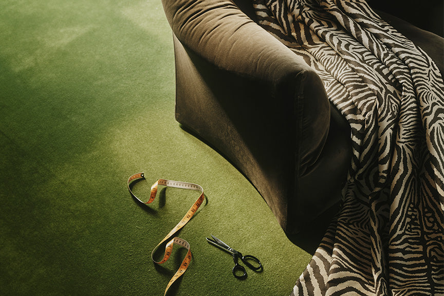 a pair of scissors and a tape measure next to a couch